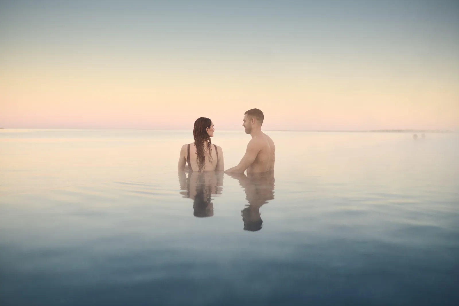 A couple soaking in the Sky Lagoon at sunset near Reykjavik